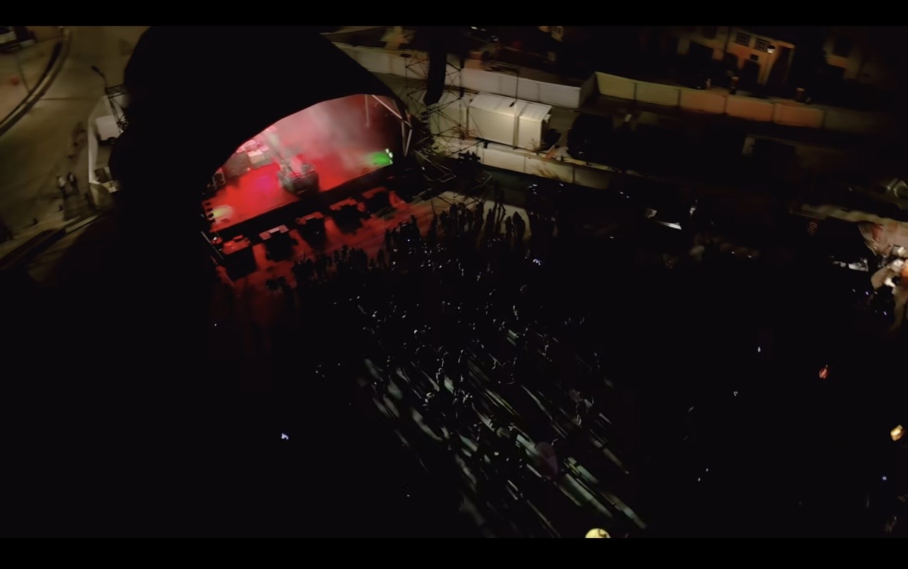 Vista aérea de palco e público em evento municipal noturno
